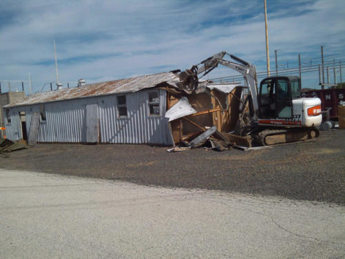 Bobcat demolishing utility shed